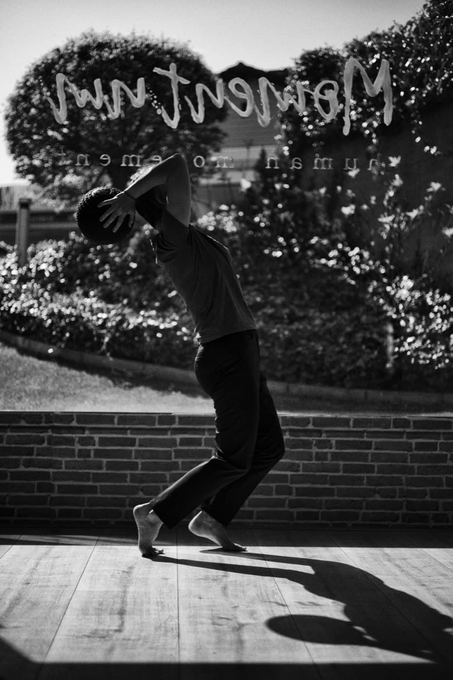 Aleksandra en plein lancer, en contre-jour devant la vitrine du studio